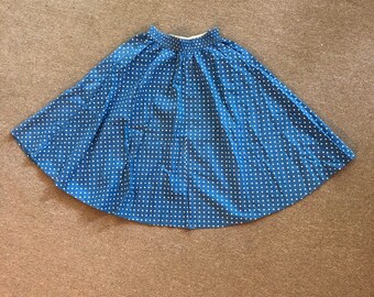 Pode incluir: Uma saia azul com bolinhas brancas. A saia tem uma silhueta evasê e uma cintura elástica.