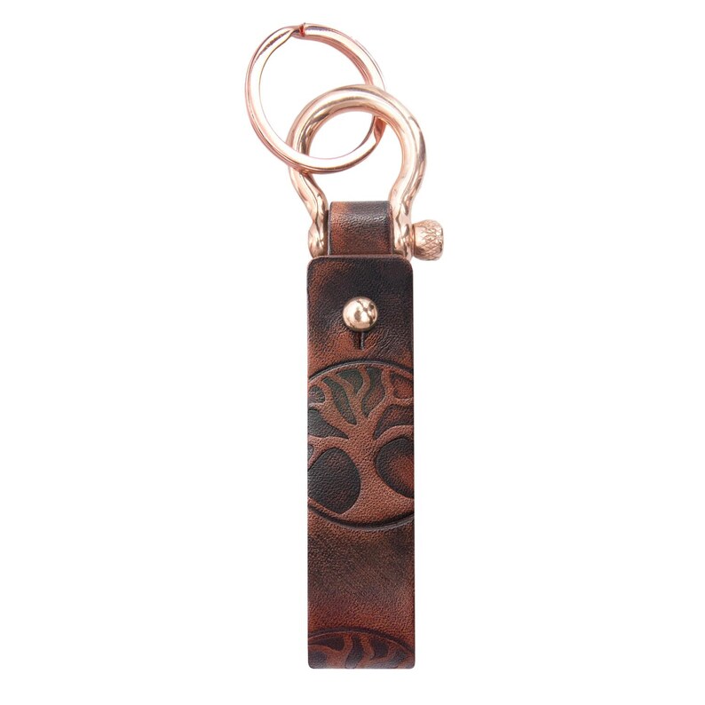 May include: A brown leather keychain with a tree design and a gold metal key ring.
