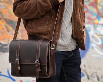 May include: A brown leather messenger bag with two buckles on the front flap. The bag has a long adjustable strap and is worn over the shoulder.
