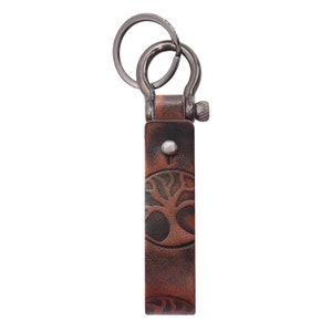 May include: A brown leather keychain with a tree design and a silver metal key ring.