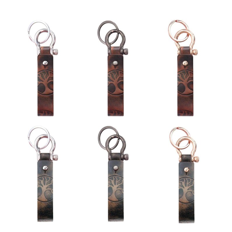 May include: Six leather keychains with a tree design. Each keychain has a different colored metal ring: silver, black, gold, silver, black, gold.