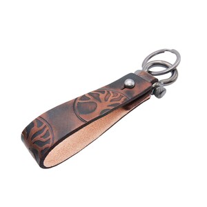 May include: A brown leather keychain with a tree design and a silver metal key ring.