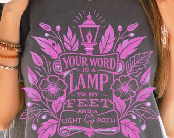 May include: A gray t-shirt with a pink floral design and the text "Your word is a lamp to my feet and a light for my path Psalm 119:105".