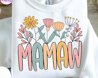 May include: White sweatshirt with a floral design and the word "MAMAW" in colorful letters. The design includes various flowers and leaves in shades of yellow, pink, and orange. The sweatshirt is a Gildan brand.