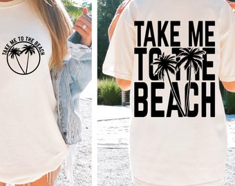 May include: White t-shirt with black text that says "Take Me To The Beach" with palm trees. The text is on the back of the shirt and the palm trees are in the middle of the text.