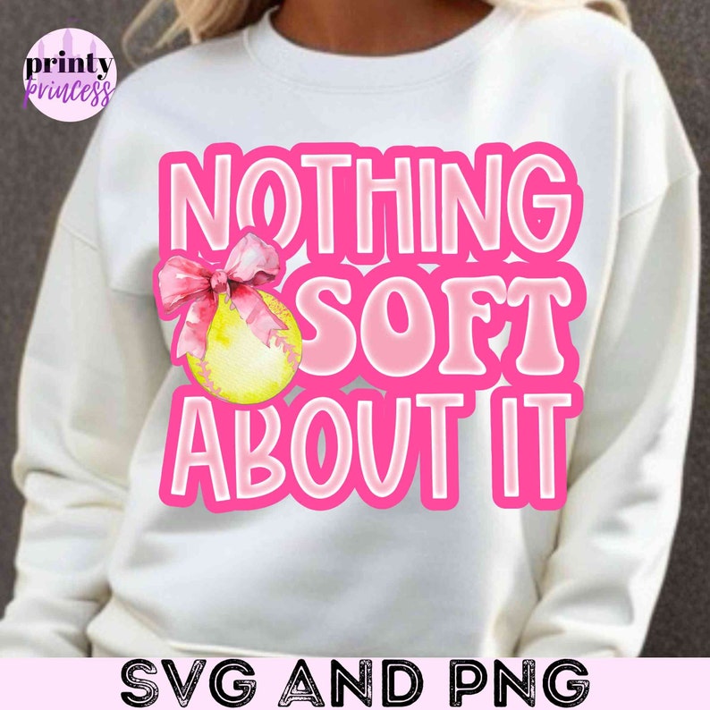 May include: White sweatshirt with pink text that reads "Nothing Soft About It" and a pink bow with a yellow softball graphic.