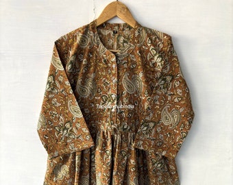 May include: A long, brown cotton dress with a paisley print. The dress has a button-up front and a gathered skirt. The dress is hanging on a wooden hanger.