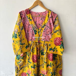 May include: A yellow floral print dress with a pink and white floral print bodice. The dress has a V-neckline and 3/4 sleeves. The dress is made of cotton and is perfect for summer.