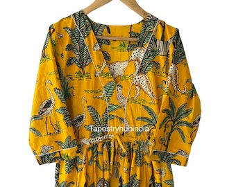 May include: A yellow cotton dress with a V-neckline and 3/4 sleeves. The dress features a jungle print with leopards, zebras, birds, and palm trees. The dress has a tie at the waist and a white trim around the neckline and sleeves. The text "Tapestryhubindia" is visible on the dress.
