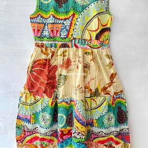Op de afbeelding: Een kleurrijke patchworkjurk met een mouwloos ontwerp. De jurk heeft een verscheidenheid aan bloemen- en geometrische patronen in tinten rood, blauw, groen, geel en bruin. De jurk heeft een gelaagde rok en een aansluitend lijfje.