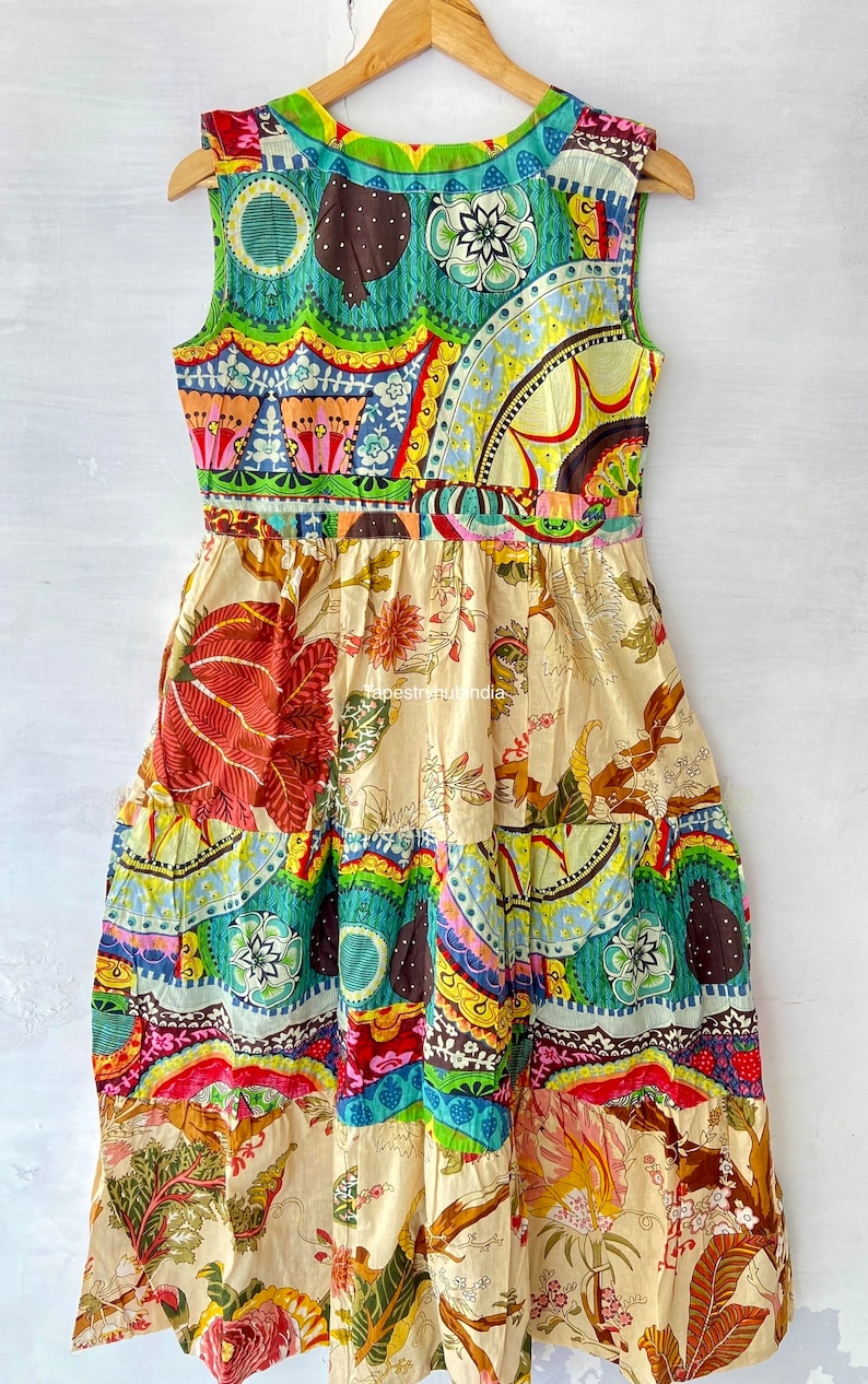 Op de afbeelding: Een kleurrijke patchworkjurk met een mouwloos ontwerp. De jurk heeft een verscheidenheid aan bloemen- en geometrische patronen in tinten rood, blauw, groen, geel en bruin. De jurk heeft een gelaagde rok en een aansluitend lijfje.