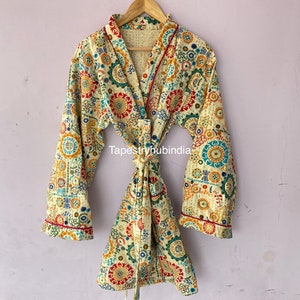 May include: A cream-colored robe with a colorful floral pattern. The robe has a tie belt and long sleeves with a red trim.