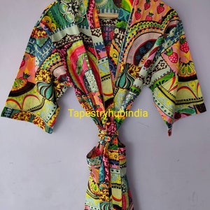 May include: A colorful, patterned robe with a tie belt. The robe has a patchwork design with various colors and shapes, including pink, green, yellow, and brown. The robe is made of cotton and has a relaxed fit.