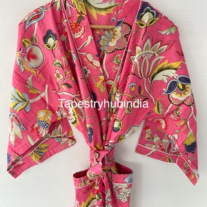 May include: Pink floral cotton robe with a white trim and a tie belt. The robe has a floral pattern with yellow, green, and blue accents. The text "Tapestryhubindia" is visible on the robe.