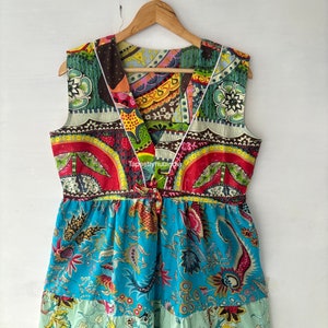 May include: A colourful patchwork dress with a V-neckline and a floral print. The dress has a fitted bodice and a flowing skirt. The fabric is a mix of different patterns and colours, including red, green, blue, and yellow.