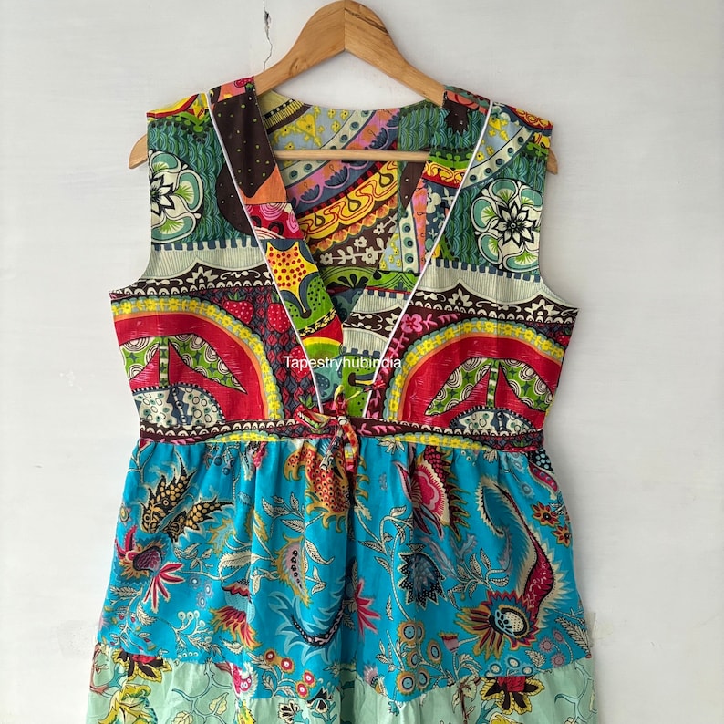 May include: A colourful patchwork dress with a V-neckline and a floral print. The dress has a fitted bodice and a flowing skirt. The fabric is a mix of different patterns and colours, including red, green, blue, and yellow.