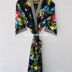 May include: Black floral print robe with white and black striped trim. The robe has a tie belt and a pocket. "Tapestryhubindia" is printed on the robe.