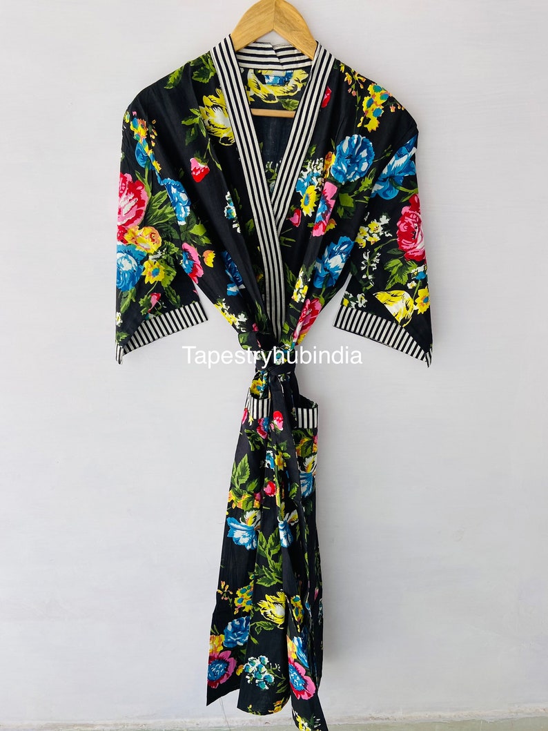May include: Black floral print robe with white and black striped trim. The robe has a tie belt and a pocket. "Tapestryhubindia" is printed on the robe.