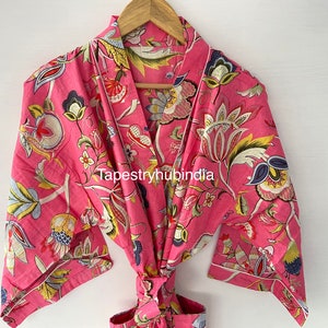 May include: Pink floral cotton robe with a tie waist and long sleeves. The robe has a white trim and a floral pattern with yellow, blue, and green accents. The text "Tapestryhubindia" is printed on the robe.