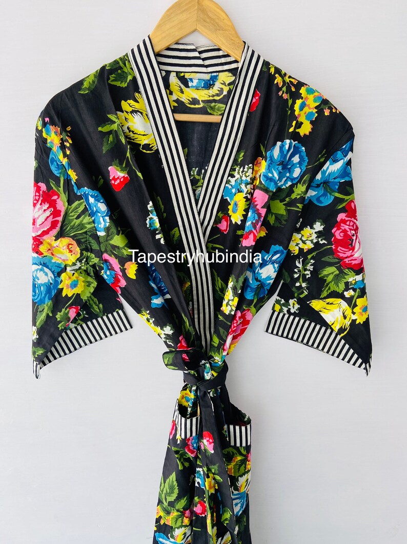 May include: Black floral print robe with white and black striped trim. The robe has a tie belt and a pocket on the left side. The text "Tapestryhubindia" is visible on the robe.