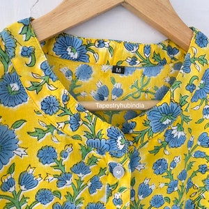 May include: Yellow cotton shirt with a blue floral print and a button fastening. The shirt has a mandarin collar and the size label says "M". The brand name "Tapestryhubindia" is printed on the label.
