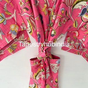 May include: Pink cotton robe with a floral print and a tie belt. The robe has a pocket on the front. The text "Tapestryhubindia" is printed on the robe.