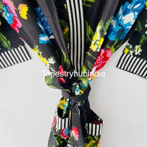 May include: Black floral print robe with a white and black striped trim. The robe has a tie belt and two pockets.