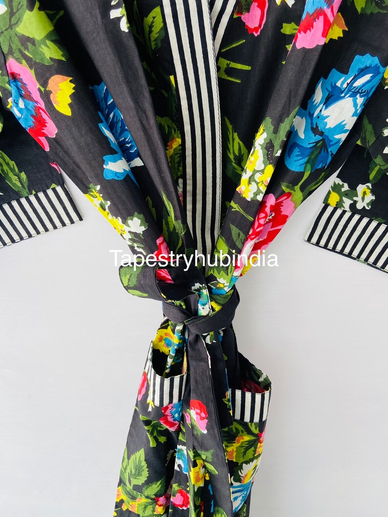 May include: Black floral print robe with a white and black striped trim. The robe has a tie belt and two pockets.