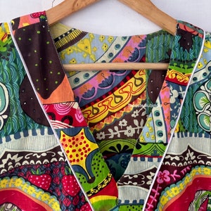 May include: Close-up of a colourful, patterned fabric with a V-neckline. The fabric is made of a patchwork of different prints, including floral, geometric, and abstract designs. The neckline is trimmed with a white piping.