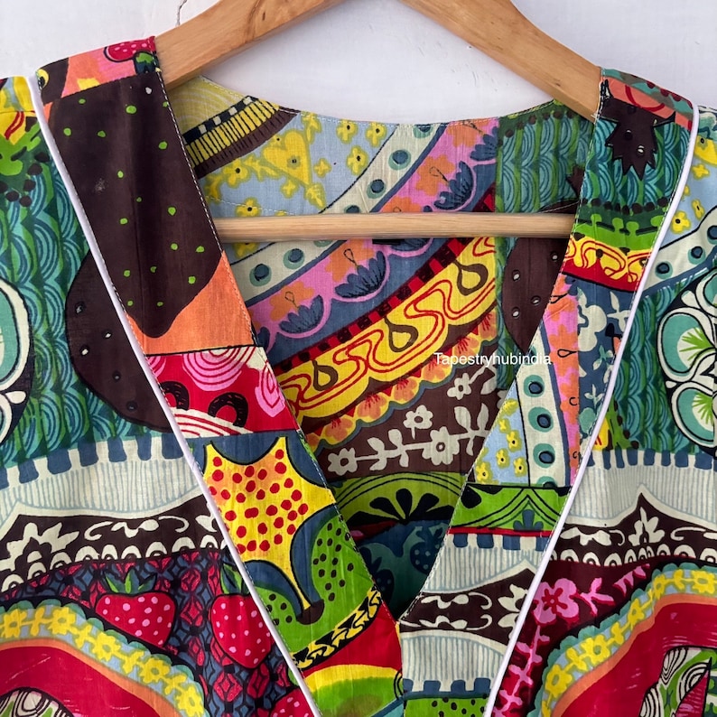May include: Close-up of a colourful, patterned fabric with a V-neckline. The fabric is made of a patchwork of different prints, including floral, geometric, and abstract designs. The neckline is trimmed with a white piping.