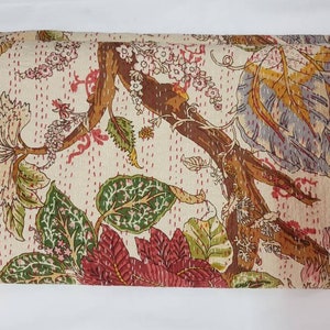 May include: A folded kantha quilt with a floral pattern in shades of brown, green, pink, and red on a cream background.