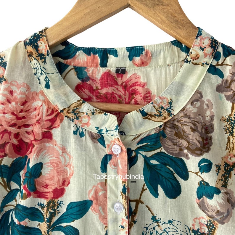 May include: A light green button-up shirt with a floral print featuring pink, teal, and brown flowers. The shirt has a mandarin collar and a single button closure. The text "Tapestryhubindia" is visible on the shirt.
