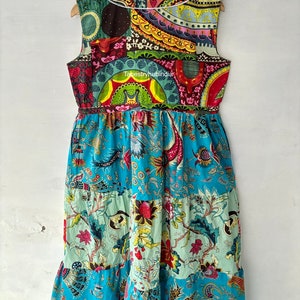 May include: A sleeveless, multi-coloured patchwork dress with a floral print. The dress has a gathered waist and a tiered skirt. The dress is made of cotton and is available in a variety of sizes.