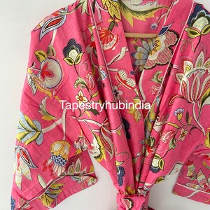 May include: Pink floral cotton robe with a tie waist and a white trim. The robe has a traditional Japanese kimono style.
