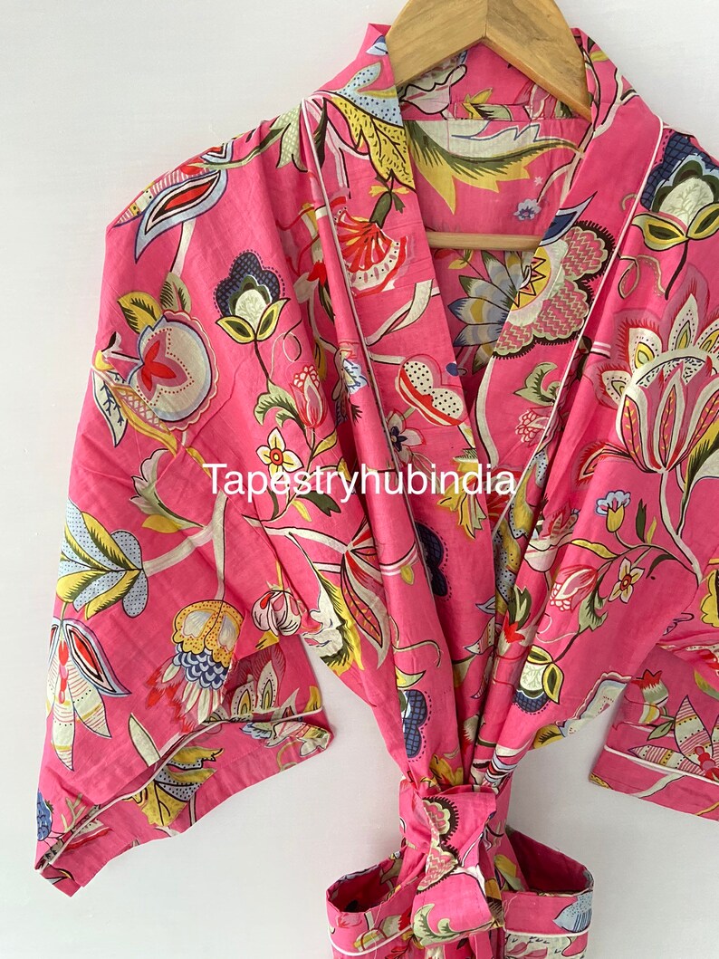 May include: Pink floral cotton robe with a tie waist and a white trim. The robe has a traditional Japanese kimono style.