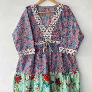 Puede incluir: Un vestido de estampado floral azul y verde con escote en V y un lazo en la cintura. El vestido tiene un ribete blanco alrededor del escote y las mangas. El vestido está hecho de algodón y es perfecto para el verano.