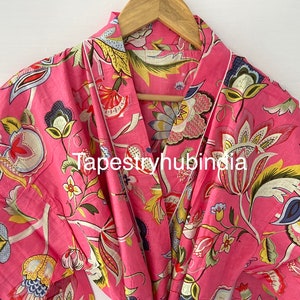 May include: A pink cotton robe with a floral print. The robe has a white trim and a tie belt. The text "Tapestryhubindia" is printed on the robe.