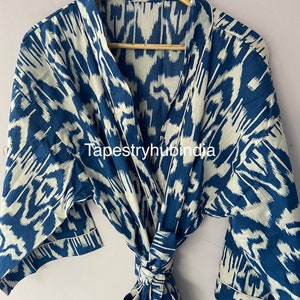 May include: A blue and white ikat patterned robe with a self-tie sash. The robe has a collar and short sleeves. The fabric has a subtle sheen.