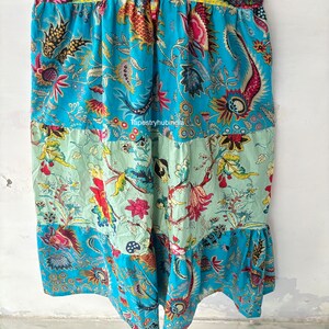May include: A blue and green patchwork skirt with a floral print. The skirt has a ruffled hem and is made of cotton fabric. The skirt is a unique and stylish piece of clothing that would be perfect for any occasion.