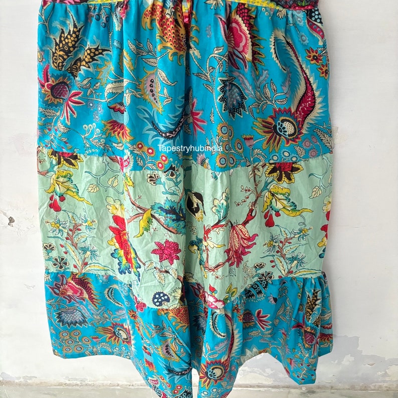 May include: A blue and green patchwork skirt with a floral print. The skirt has a ruffled hem and is made of cotton fabric. The skirt is a unique and stylish piece of clothing that would be perfect for any occasion.