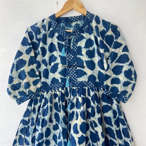 May include: A blue and white cotton dress with a tie-up neckline and a tie at the waist. The dress has a floral pattern and is made in India.