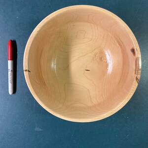 May include: A large, round wooden bowl with a natural wood finish. The bowl is empty and has a smooth, polished surface.
