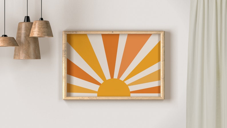 May include: A framed print of a stylized sun with orange, yellow, and white rays. The sun is set against a cream background.