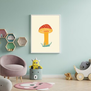 May include: A framed art print showing a mushroom illustration. The mushroom has a red and white spotted cap, an orange stem, and green grass. The artwork is displayed in a child's room with other decorative items, such as a chair and toys.