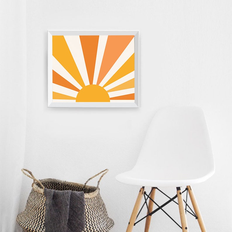 May include: A framed print of a stylized sun with orange and yellow rays. The sun is set against a white background.