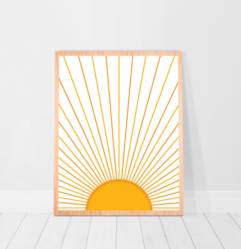 May include: A framed print of a stylized sun with yellow rays radiating out from a yellow circle. The background is white.