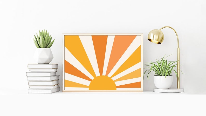 May include: A framed print of a stylized sun with orange, yellow, and white rays. The sun is set against a white background.