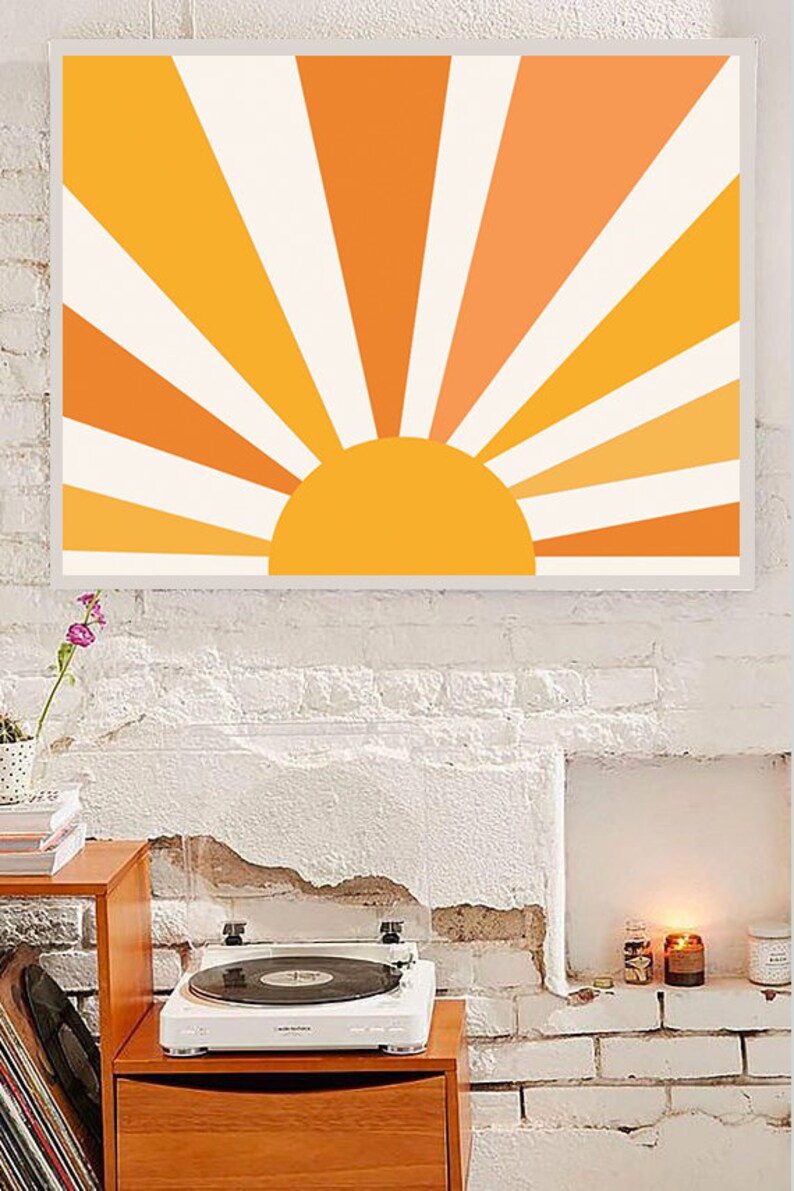 May include: A framed print of a stylized sun with orange and yellow rays against a white background. The sun is a solid yellow circle.