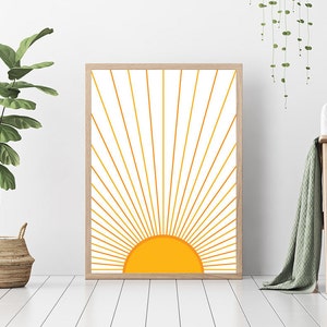 May include: A framed print of a stylized sun with yellow rays radiating outward on a white background.
