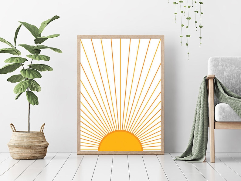 May include: A framed print of a stylized sun with yellow rays radiating outward on a white background.